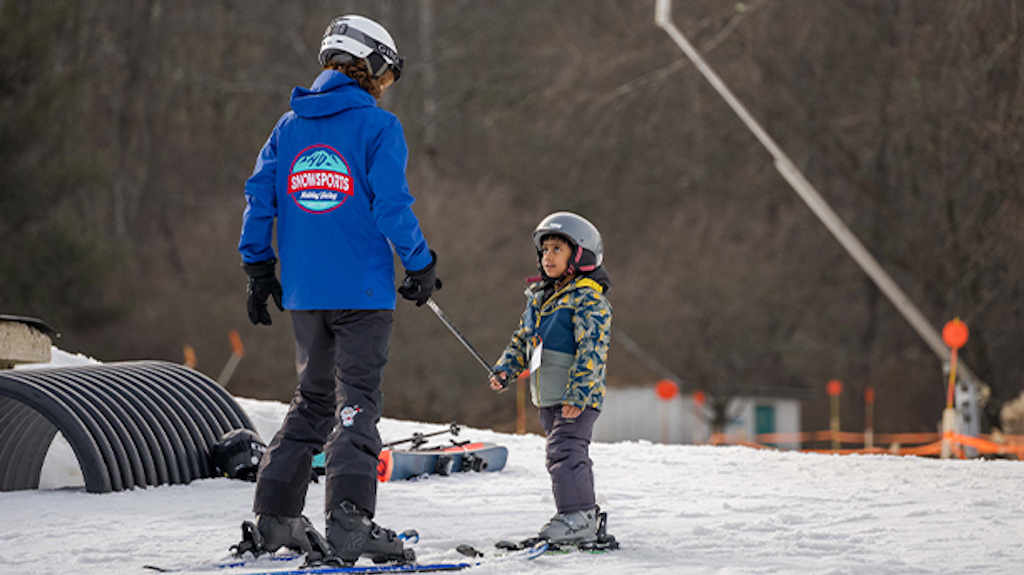 A ski instructor works with a small child as they learn to ski.